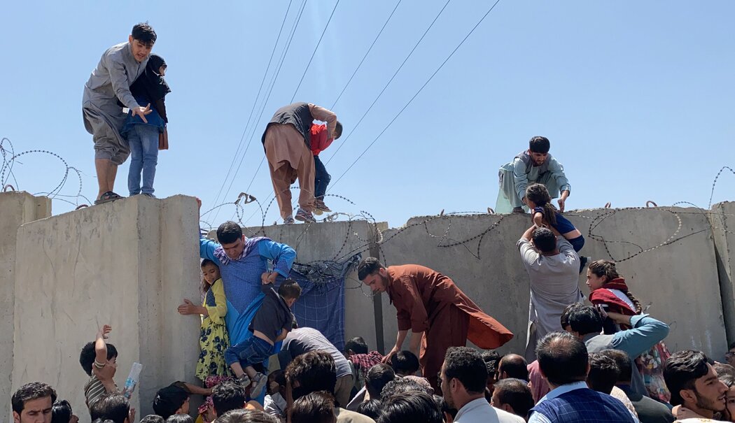 人们拼命越过哈米德·卡尔扎伊国际机场的边界墙逃离阿富汗